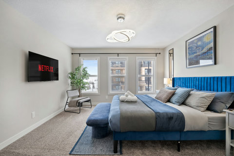 Luxurious master bedroom featuring a stunning blue upholstered headboard and urban views