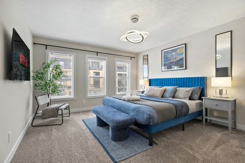 Stylish master bedroom featuring a striking blue bed frame and floor-to-ceiling windows