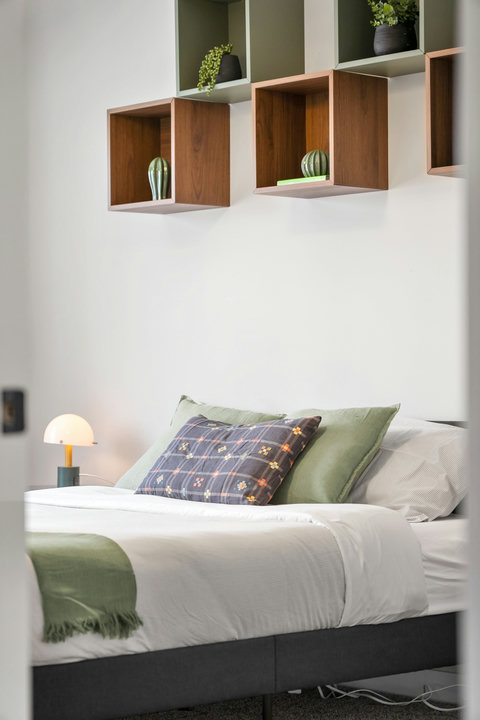 Stylish guest bedroom with designer floating shelves and warm accents