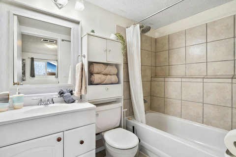 Clean and bright master bathroom with ample storage and shower tub combo