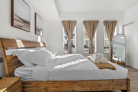 Sunny master bedroom with wooden furnishings and stunning city views