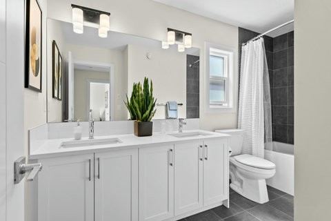 Bright shared bath featuring dual sinks and a relaxing soaker tub