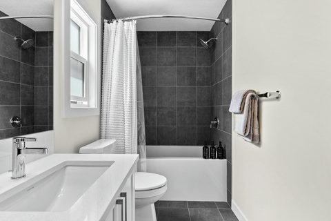 Refresh in this sleek bathroom with dark tiles and soaking tub