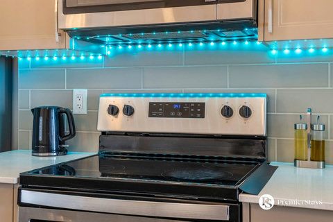 Sleek kitchen featuring stainless steel appliances and ambient blue lighting