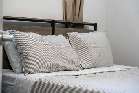 Cozy guest bedroom with crisp striped bedding and modern headboard design