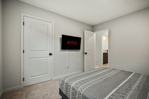 Comfortable guest bedroom with entertainment setup and ensuite access