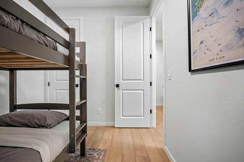 Comfortable guest bedroom featuring practical bunk beds and warm wood floors