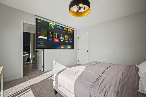 Comfortable guest bedroom with entertainment TV and natural light