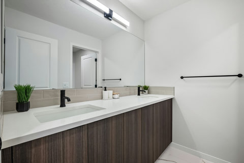 Spacious dual vanity bathroom with sleek black fixtures and soft lighting
