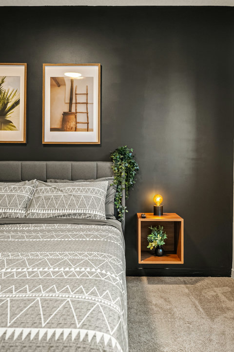 Stylish bedroom featuring cozy geometric bedding and warm ambient lighting.