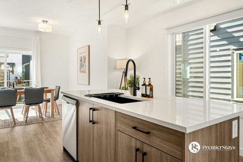 Sleek modern kitchen featuring a spacious island with black undermount sink and contemporary pendant lights