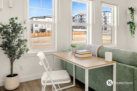 Sunny living room with comfortable seating and expansive windows overlooking the neighborhood