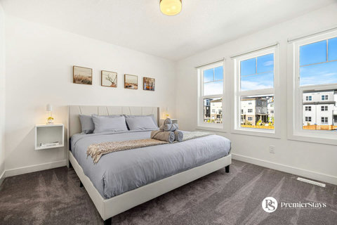 Sunlit master bedroom with expansive windows overlooking the neighborhood