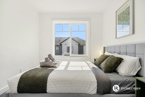 Sunlit guest bedroom with plush bedding and neighborhood views