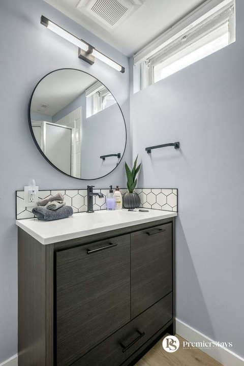 Spa-inspired bathroom with stylish round mirror and contemporary fixtures