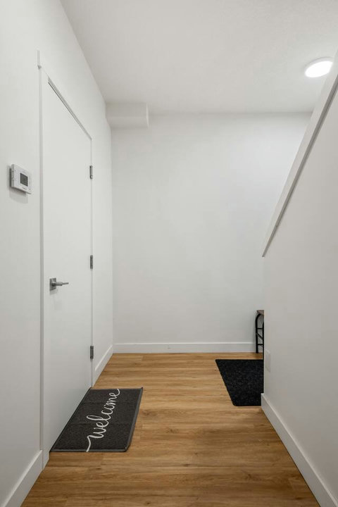 Bright welcoming entryway with warm wood floors and clean white walls