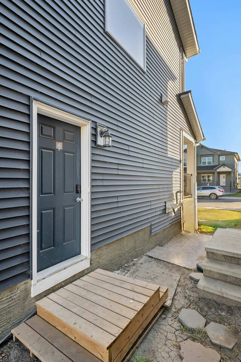 Welcoming side entrance with charming wooden deck and modern door