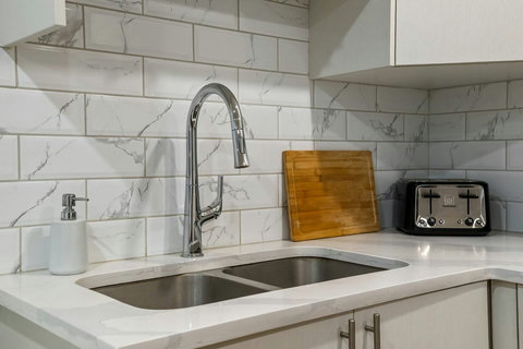 Sleek kitchen featuring marble subway tiles and contemporary stainless steel fixtures