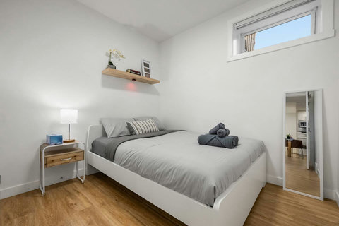 Light-filled guest bedroom with crisp white bed and natural wood floors