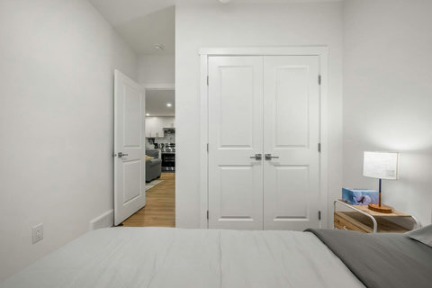 Comfortable guest bedroom with ample storage and warm wood flooring