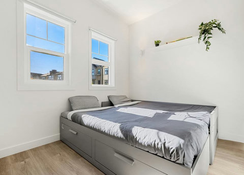 Cozy guest bedroom flooded with natural light and urban views