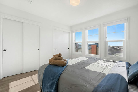 Sunlit master bedroom with panoramic windows overlooking the cityscape