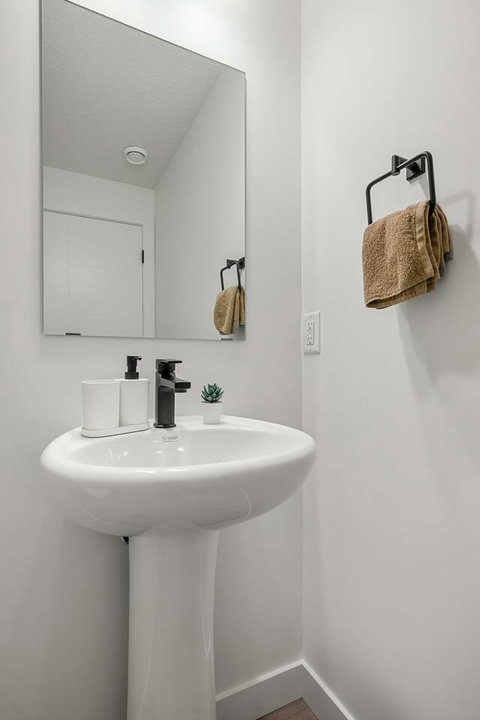 Bright, contemporary half bath with sleek black fixtures and natural light