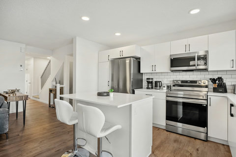 Bright modern kitchen featuring white cabinetry, stainless steel appliances, and island seating
