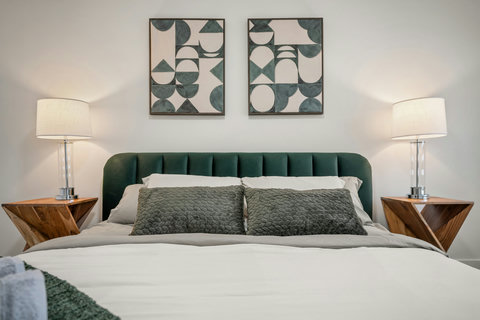 Stylish master bedroom with plush green headboard and curated wall art