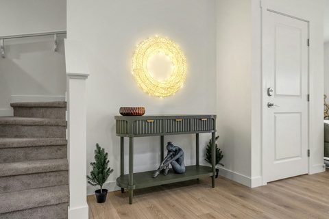 Welcoming entryway with striking illuminated wall art and olive-toned console