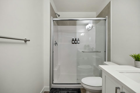 Sleek modern bathroom featuring spacious glass shower and elegant white vanity