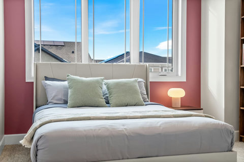 Cosy bedroom with warm accent wall, full bookshelf and dedicated desk space