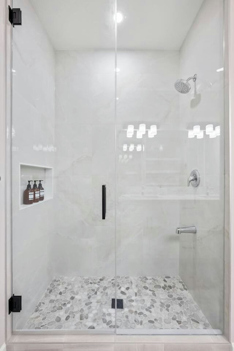 Refresh in a spa-like glass shower with marble surround and pebble stone floor