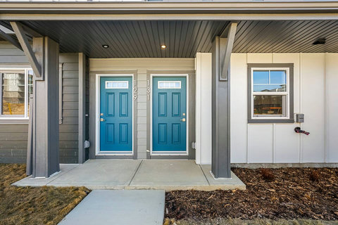 Welcoming front entrance with distinctive teal doors and covered porch