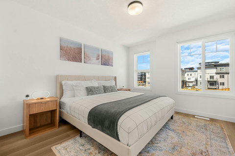 Sunny main bedroom with comfortable queen bed and urban views