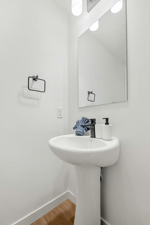 Clean and bright half bathroom with modern fixtures and ample lighting
