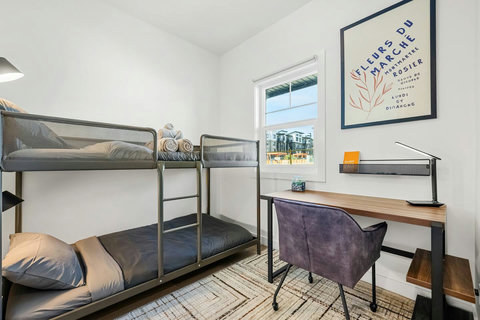 Bright shared bedroom with metal bunk beds and dedicated study space.