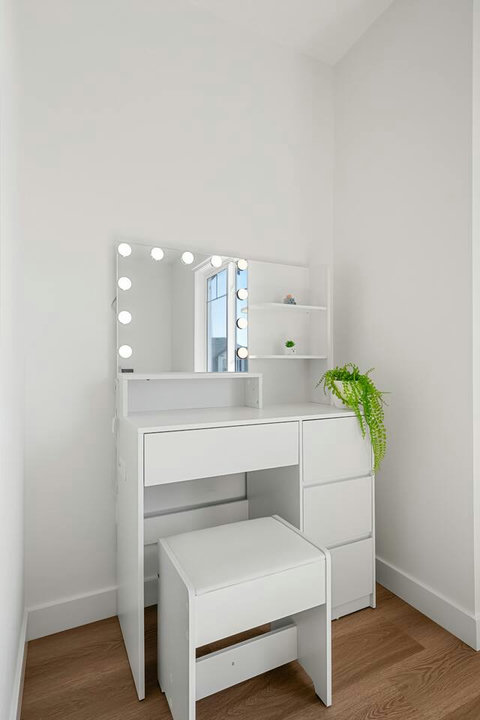 Stylish bedroom vanity with Hollywood-style lighting and open shelving.