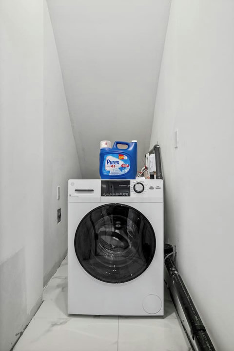 Convenient in-unit laundry room with modern front-load washer and detergent