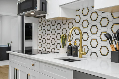 Sleek kitchen featuring honeycomb tile backsplash and brass fixtures throughout.