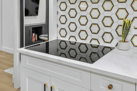 Sleek modern kitchen featuring induction cooktop and stylish geometric backsplash