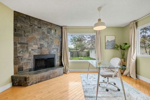 Sunny living room with stone fireplace and backyard views