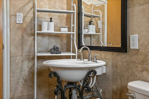 Beautiful pedestal sink with ornate iron detailing and organized shelving