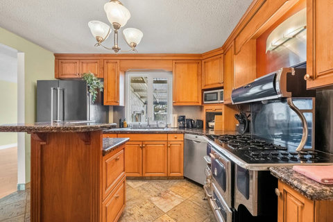 Warm wood cabinetry and granite countertops create an inviting culinary space.