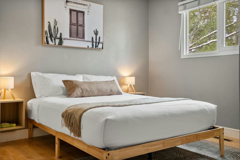 Comfortable guest bedroom with warm wood frame and plenty of natural light