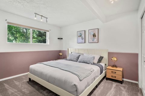 Comfortable guest bedroom with cream upholstered bed and plenty of natural light.