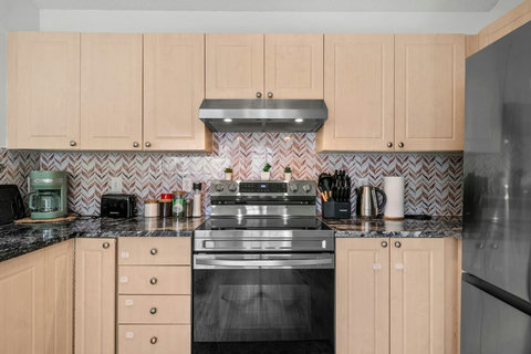 Fully equipped kitchen with stainless steel appliances and herringbone backsplash