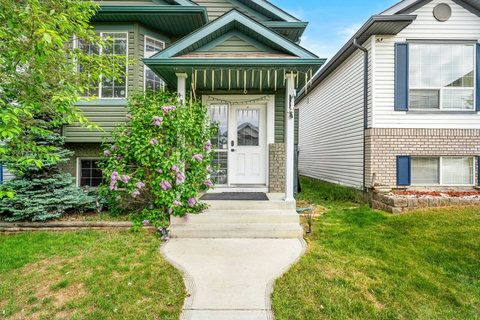 Charming front entrance framed by blooming purple flowers and lush greenery