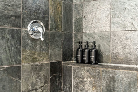 Beautiful stone-tiled shower with premium bath amenities and modern fixtures