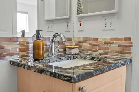 Elegant bathroom featuring granite countertop and warm brick tile backsplash